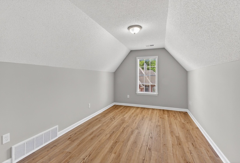 Attic space with sloped ceilings and light wood-finish flooring