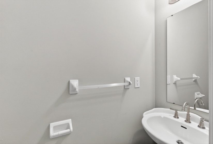 Pedestal sink with a brushed nickel faucet, framed by a rectangular mirror