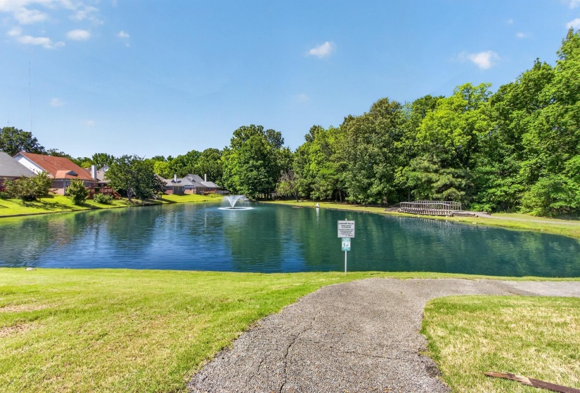 Community pond with a central fountain, surrounded by mature trees and a manicured lawn