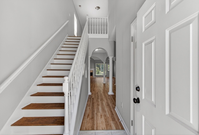 Entry foyer featuring wood-finish flooring, a paneled front door, and a staircase with white risers and wood treads