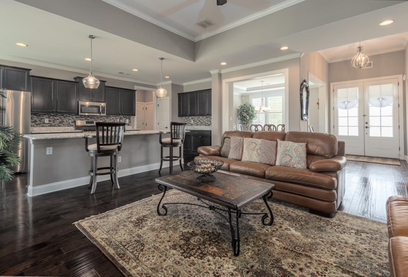Open-concept living area with dark wood-finish flooring, a kitchen island featuring a light-colored countertop, and recessed lighting