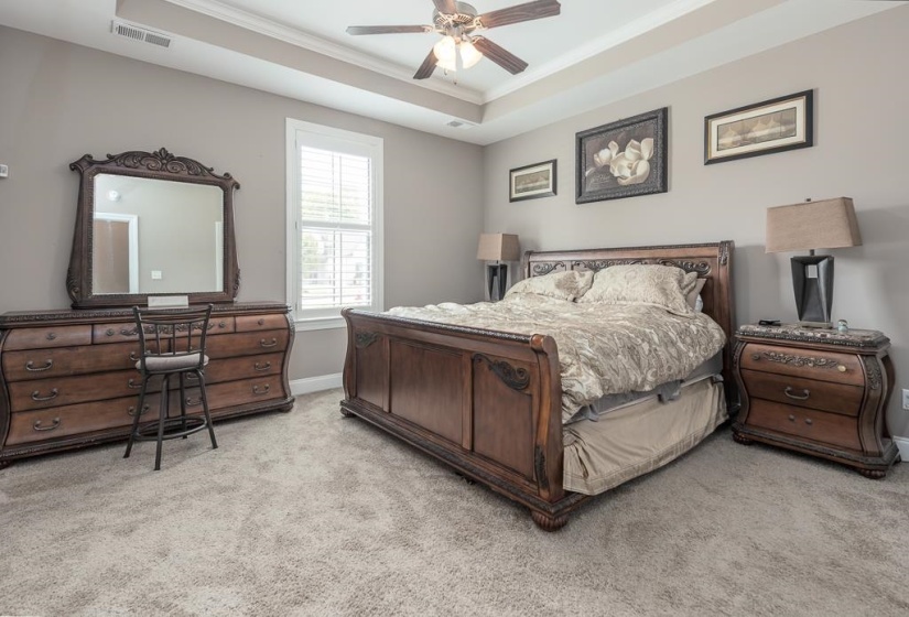 Bedroom featuring a tray ceiling with crown molding, ceiling fan, and light gray wall paint