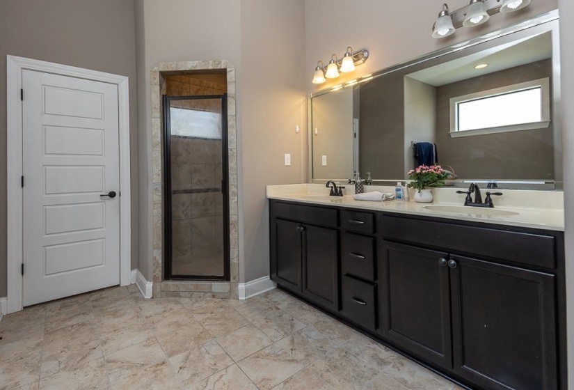 Bathroom featuring a dual vanity with dark wood cabinetry and light countertops