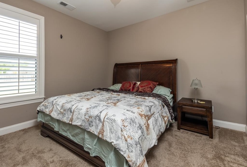 Bedroom featuring neutral wall paint, white trim, plantation shutters, and carpeted flooring