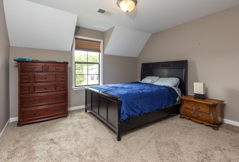 Carpeted room featuring a window with a natural light-filtering blind, sloped ceilings, and a flush mount ceiling light fixture