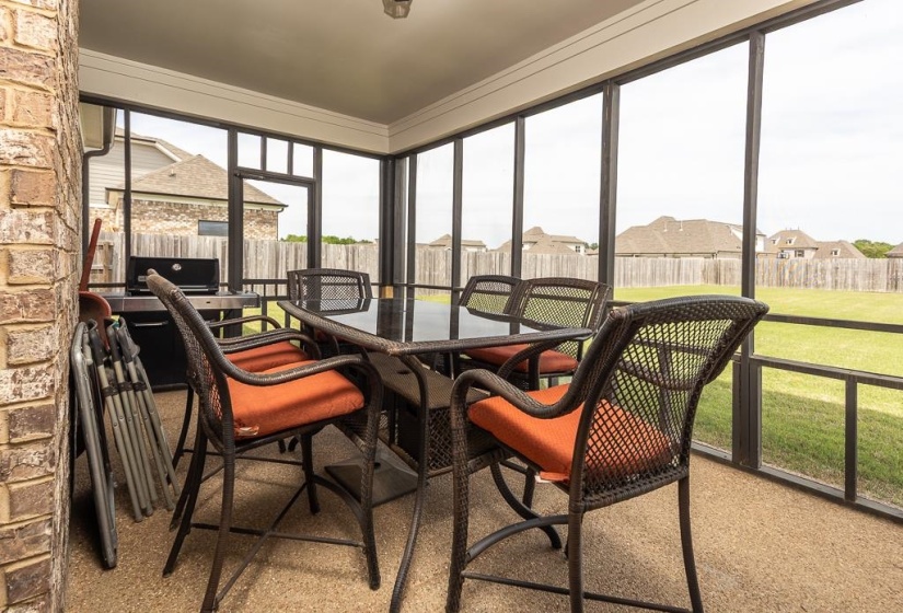Screened outdoor patio featuring a brick exterior wall and a granular concrete floor