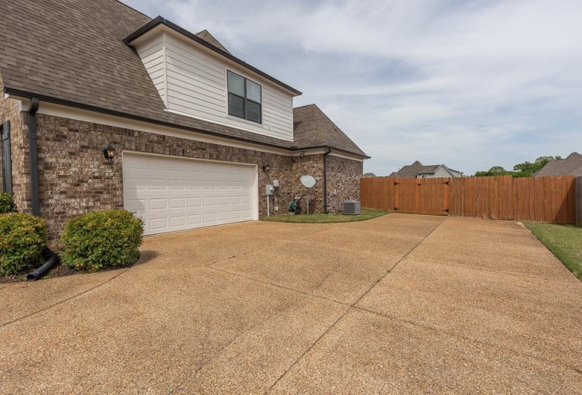 Expansive exposed aggregate concrete driveway leading to a two-car garage