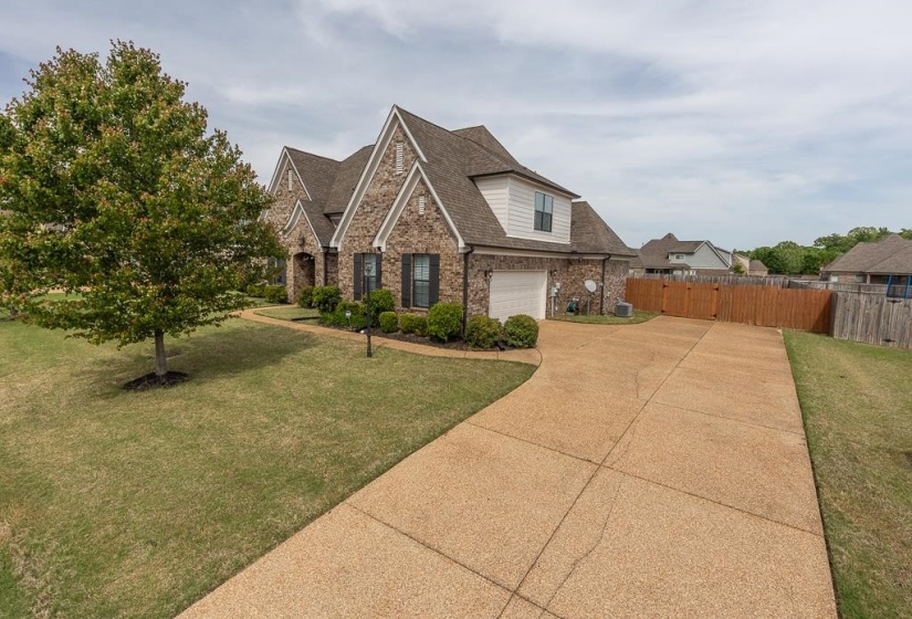 Brick facade residence with gabled rooflines, an attached garage, and a gravel-finish driveway