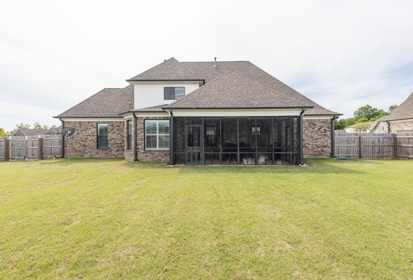 Expansive backyard featuring a screened porch, brick exterior, and a privacy fence