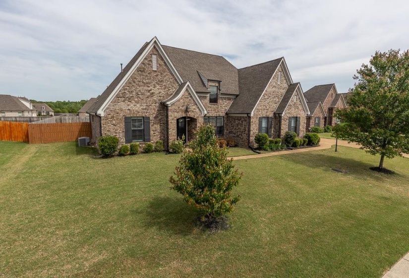 Brick exterior with multiple gables, dark shutters, and a prominent front entry