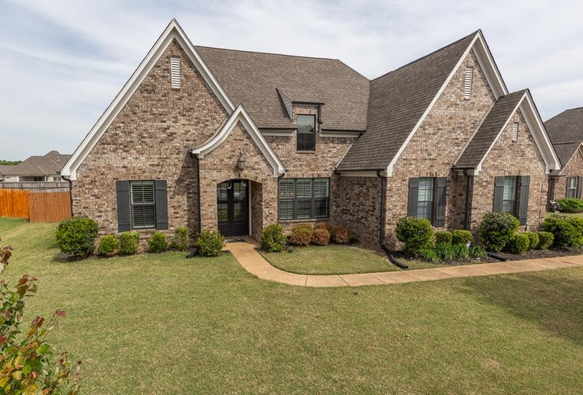 Brick exterior with a gabled roofline, dark shutters, and a covered entryway
