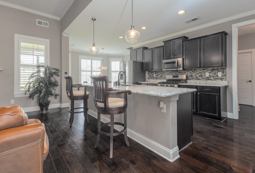 Kitchen featuring dark wood-finish cabinetry, stainless steel appliances, and a mosaic tile backsplash