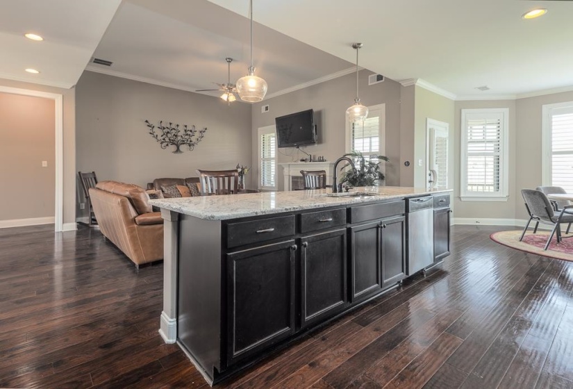 Kitchen island featuring dark cabinetry, a light-toned countertop, and an undermount sink with a gooseneck faucet