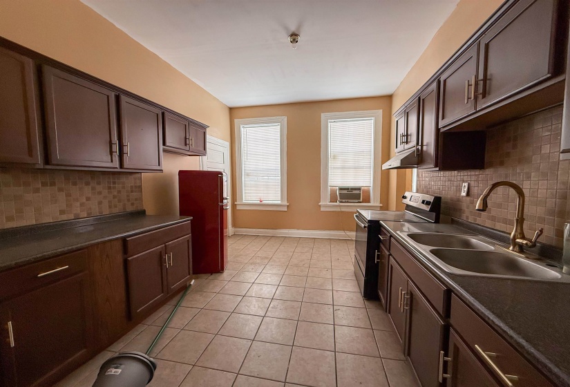 Kitchen featuring extensive dark wood cabinetry, tile flooring, and a tiled backsplash