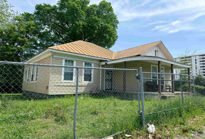 Exterior featuring a metal roof, front porch, and chain-link fencing