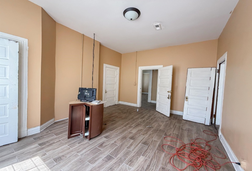 Spacious interior room featuring tile flooring, neutral wall tones, and multiple panel doors with white trim