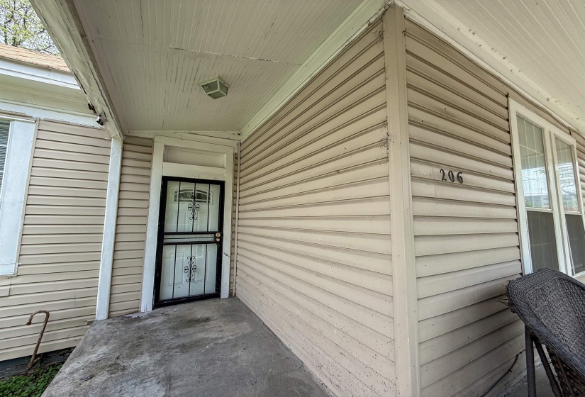 Front entry featuring a security screen door, concrete landing, and light-colored siding