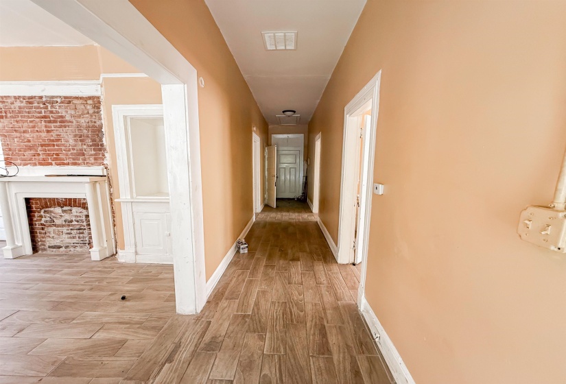 Hallway featuring wood-finish flooring, light peach wall paint, white trim, and multiple doorways