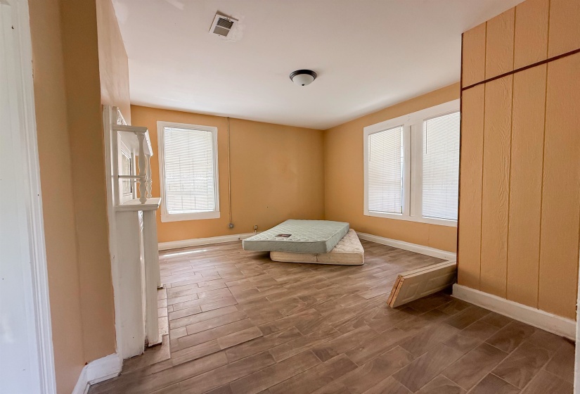 Room featuring wood-finish flooring and two windows with blinds