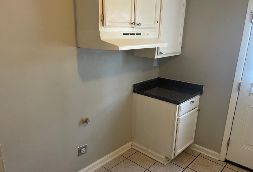 Washroom with electric dryer hookup, light tile patterned floors, and baseboards