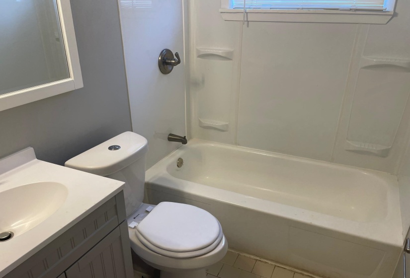 Bathroom with toilet, vanity, and  shower combination