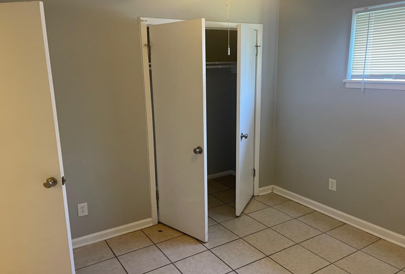 Unfurnished bedroom with light tile patterned floors, baseboards, and a closet