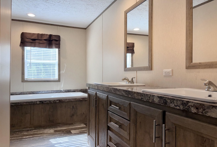 Dual vanity featuring wood-finish cabinetry, granite-patterned countertops, and undermount sinks