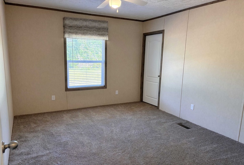 Carpeted room featuring a single window with blinds and a fabric valance