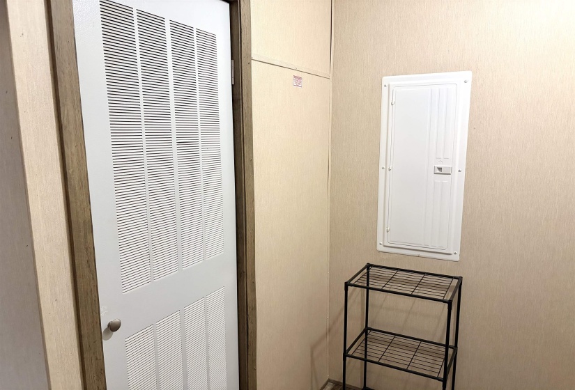 White louvered door, neutral wall covering, and a recessed electrical panel