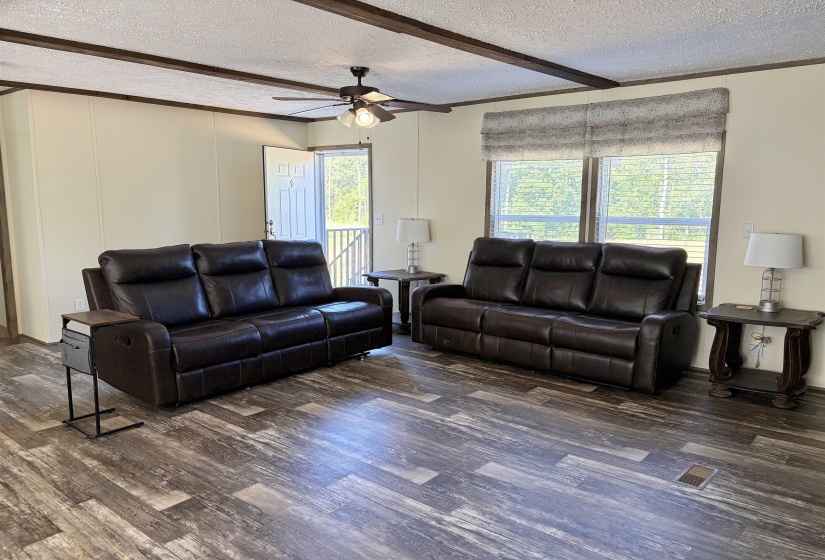 Open-concept living area featuring wood-finish flooring, exposed ceiling beams, and a ceiling fan