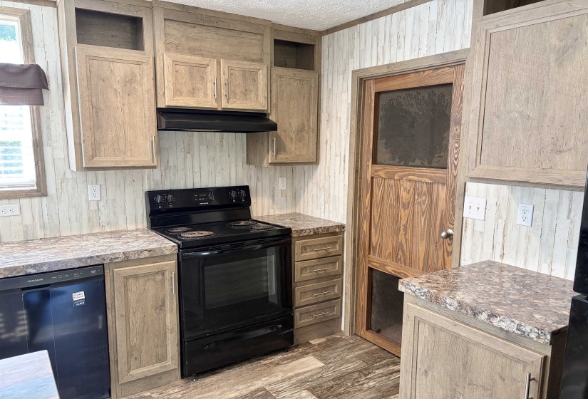 Kitchen featuring wood-finish cabinetry, speckled laminate countertops, a black electric range with coordinating range hood, and a black dishwasher