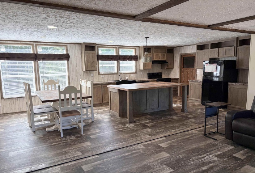 Open-concept living area featuring wood-finish flooring and exposed ceiling beams