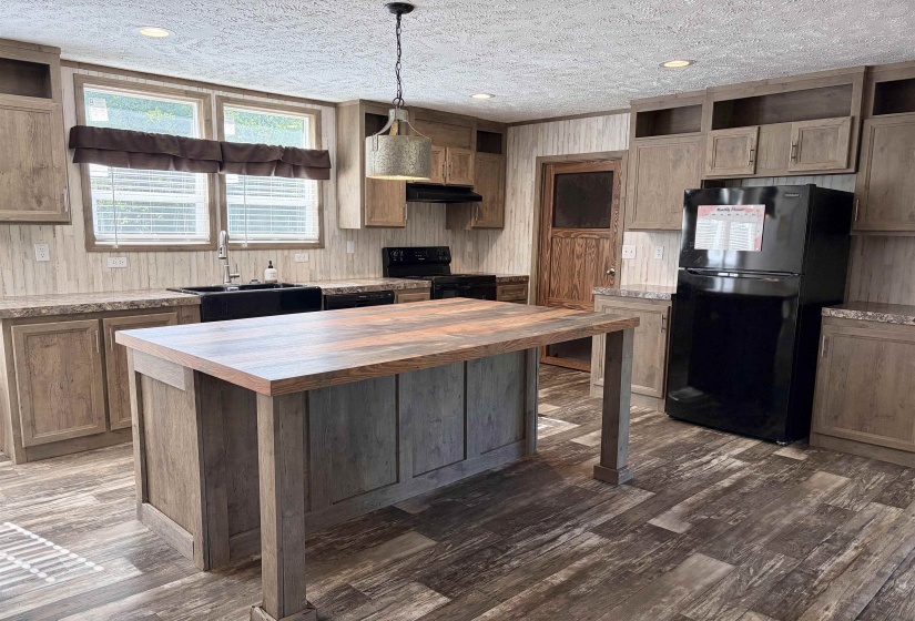 Kitchen featuring a wood-finish island with a contrasting countertop, coordinating wood-finish cabinetry, a black basin sink, and wood-finish flooring