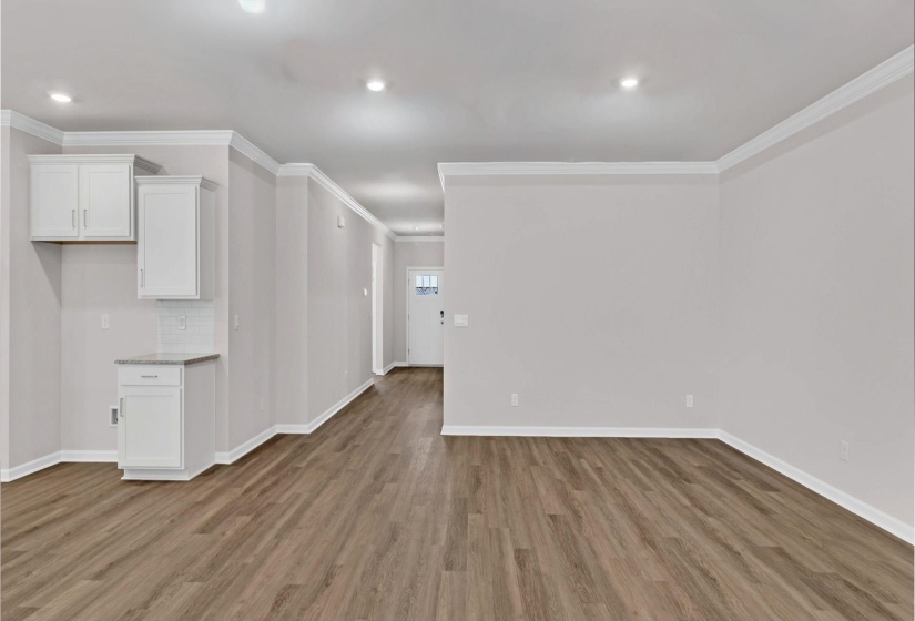 Unfurnished living room featuring ornamental molding, light wood-style flooring, and recessed lighting