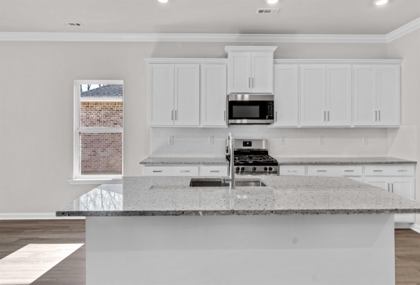 Kitchen featuring dark wood-style floors, white cabinets, stainless steel appliances, light stone counters, and backsplash