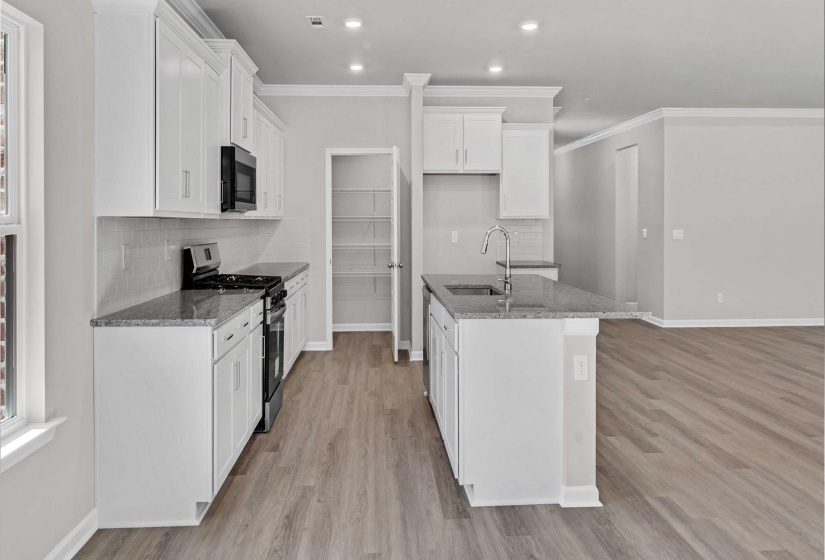 Kitchen with stainless steel range with gas stovetop, backsplash, white cabinets, dark stone countertops, and ornamental molding