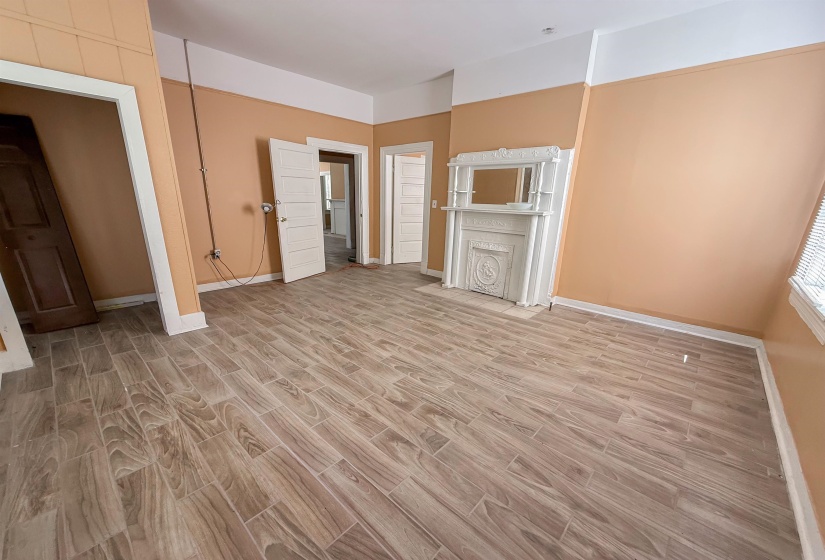 Room featuring wood-finish plank flooring and a decorative fireplace with an ornate mantel and mirror