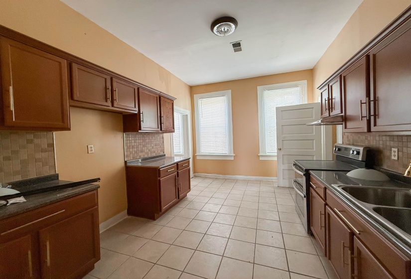 Kitchen featuring wood-finish cabinetry, tile flooring, and integrated stainless steel double sink