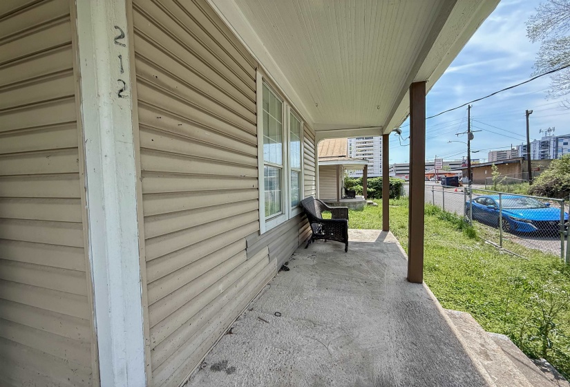 Front porch with concrete flooring and supporting columns, featuring beige horizontal siding