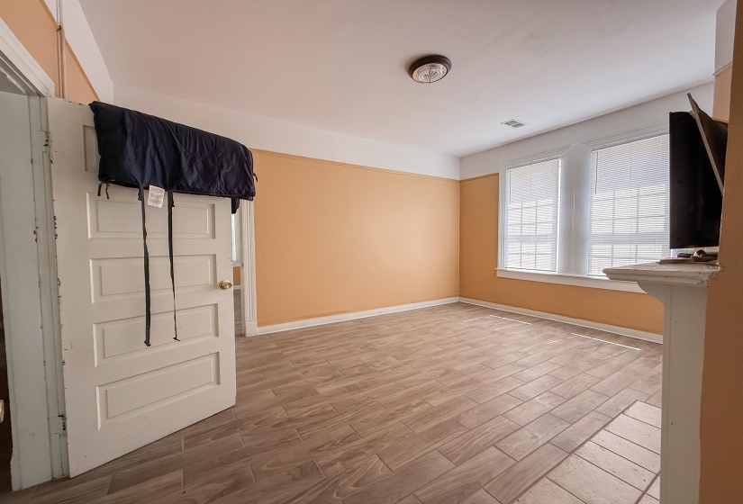 Room featuring wood-finish tile flooring, two paneled windows with blinds, a built-in mantel, and a flush-mount ceiling light fixture