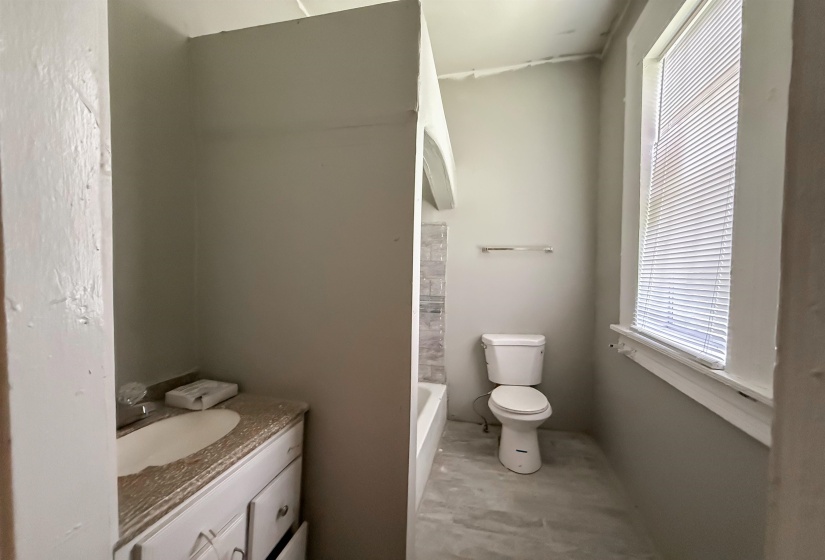 Bathroom with a white vanity featuring a built-in sink and a patterned countertop