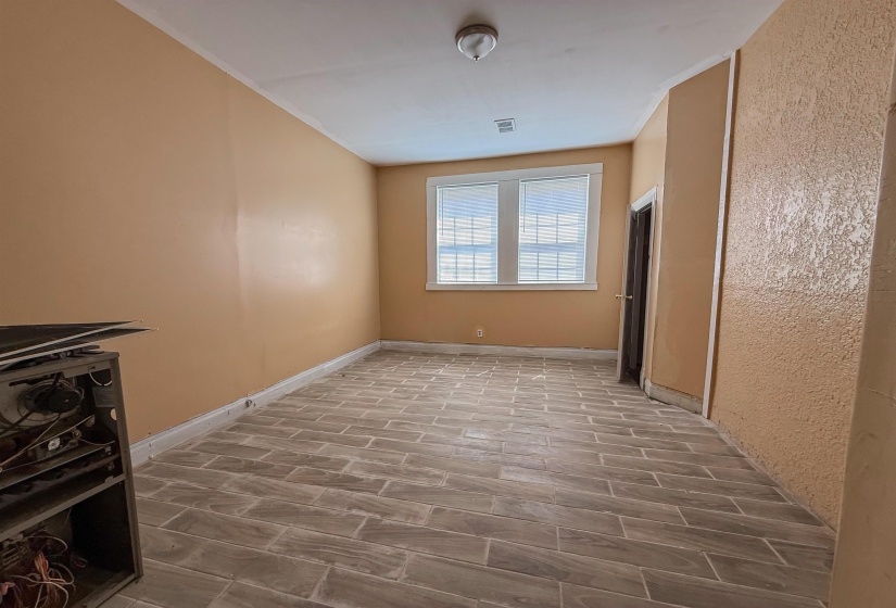 Room featuring plank-style tile flooring, dual windows with blinds, a dark wood-finish door, and a flush-mount ceiling light