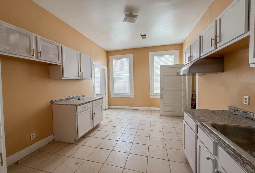 Spacious kitchen featuring white cabinetry, light-toned tiled flooring, and multiple windows
