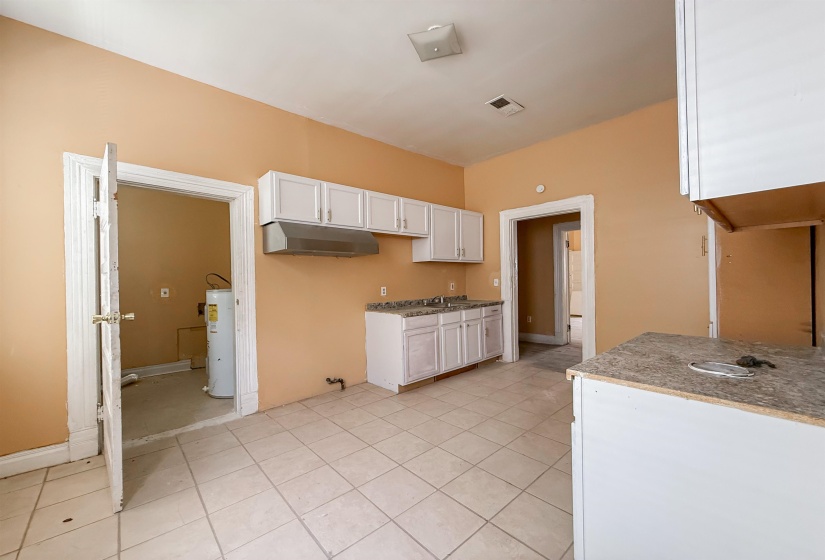Kitchen area with white cabinetry, a double basin sink, and a range hood