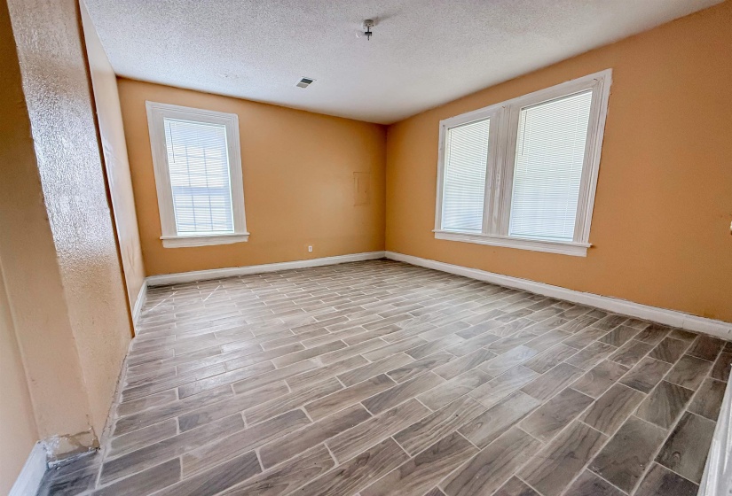 Spacious room featuring wood-finish tile flooring and three windows with white trim