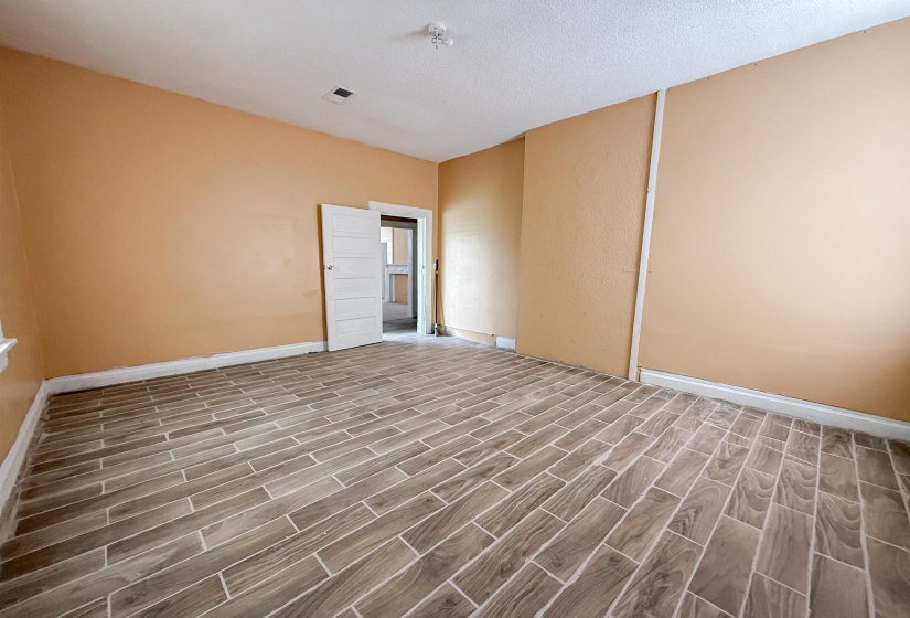 Wood-look tile flooring in a diagonal pattern, neutral-toned walls, white baseboards, and a white paneled door