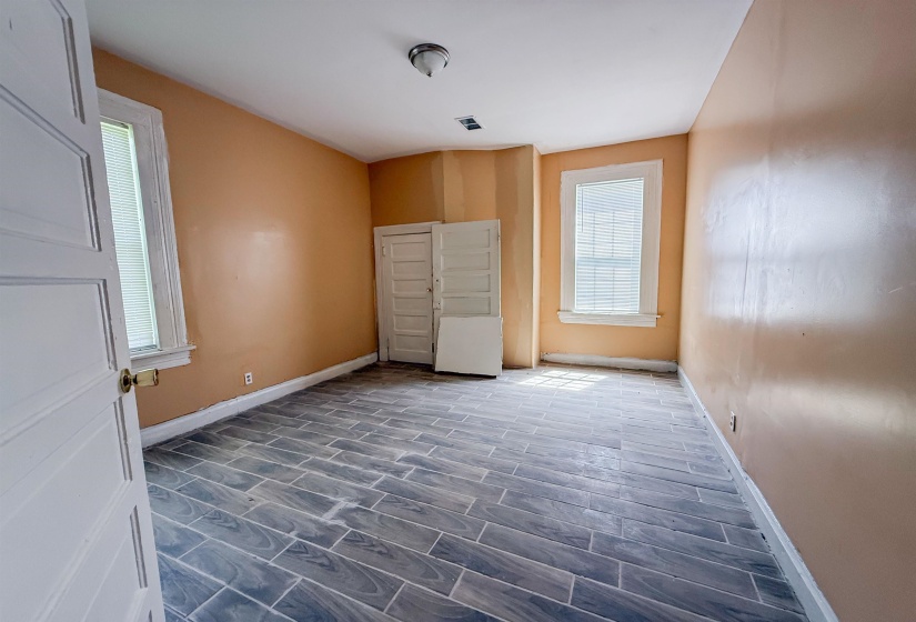 Room featuring wood-finish tile flooring, two windows with white trim, and a built-in closet with bifold doors