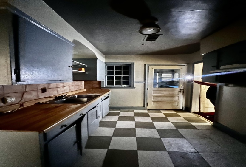 Kitchen with dark floors, backsplash, and butcher block counters