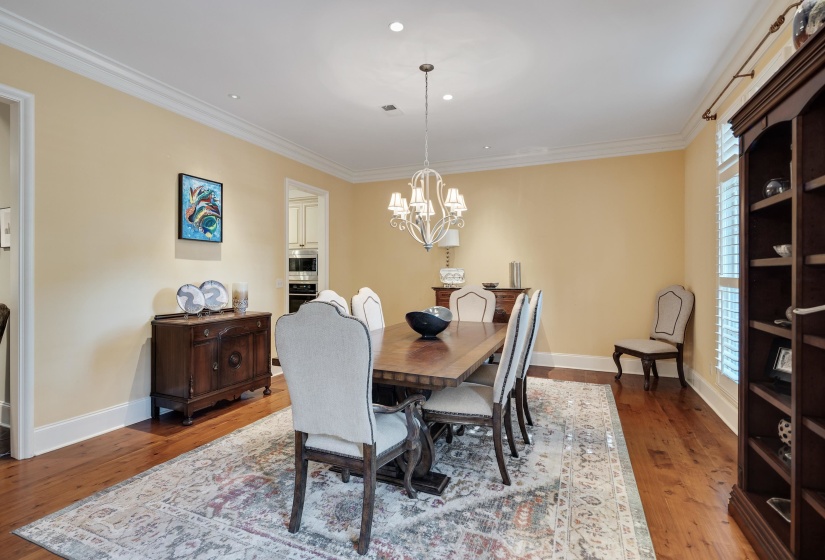Spacious dining area featuring hardwood flooring, crown molding, recessed lighting, and a decorative chandelier