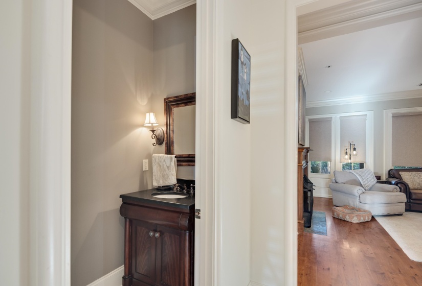 Powder room featuring an ornate wood-framed mirror, a single sconce light fixture, and a dark wood vanity with an integrated sink and dark countertop